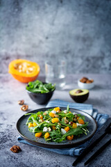 Roasted pumpkin avocado arugula goat cheese salad in a plate
