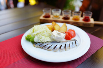 Traditional Lithuanian marinated herring served with sour cream, fresh vegetables and hot boiled potatoes.