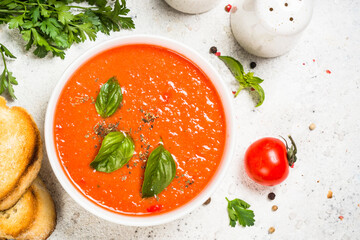 Tomato soup or gazpacho with basil. Summer cold vegan dish. Top view at white background.