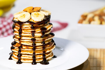 Pancakes with Chocolate Syrup, Nuts and Bananas. Stack of whole flapjack. Tasty breakfast and Healthy Food