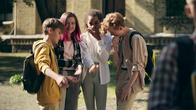 Group of school children gossiping and laughing at insecure classmate, bullying