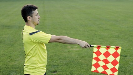 Assistant referee moving along the sideline during a soccer match. Linesman hand with flag...