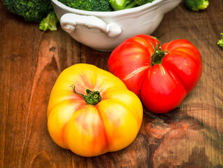 whole red and yellow heirloom tomatoes on wood surface tabletop cutting board