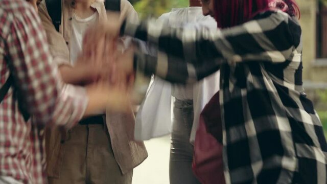 Cheerful teenagers stacking hands, ready to carry out task together, teamwork