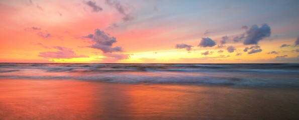 Baltic sea at sunset. Dramatic twilight sky, blue and pink glowing clouds, golden sunlight. Waves,...