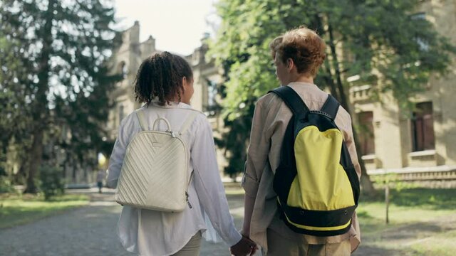 Multiethnic couple of kids holding hands, walking to school together, first love