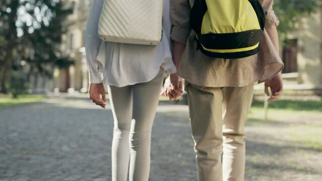 Male and female school students holding hands, romantic date after classes