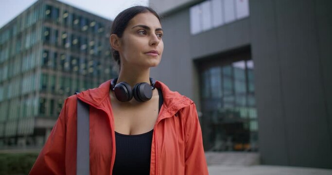 Woman athlete dressed in windbreaker has daily physical activities works on muscle strength improves body does exercises essential for every human walks in downtown going to conduct practice session