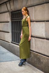Woman Relaxing on Street. Dressing in a green, long Maxi Tank Dress,  black dress sandals, a young black lady is standing by old fashion style window and wall,  looking down, sad, lost in thought.