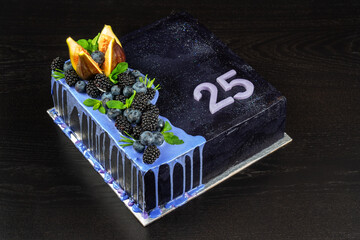 Beautiful conceptual fruit black square buttercream cake. On a wooden table.