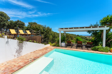 Gazebo in the garden near the pool with a view of the pine forest, a place for tourists to relax. Sun beds for sunbathing.