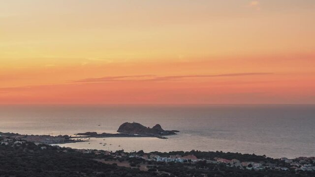 Time-lapse of sun setting over the red rock, La Pietra, the Mediterranean sea and lights coming on at Ile Rousse in the Balagne region of Corsica