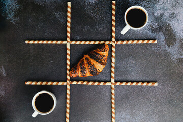 Businessman working morning with cups of hot coffee and sweet croissants on black background. Game...