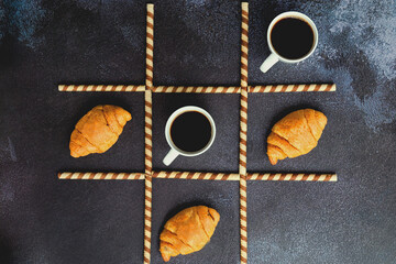 Businessman working morning with cups of hot coffee and sweet croissants on black background. Game...