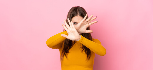 Young caucasian woman isolated on pink background nervous stretching hands to the front