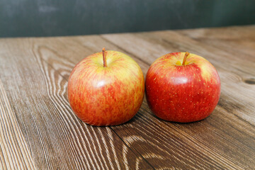Two apples on wooden table, with black background.