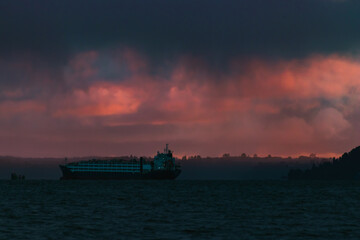 A lonely ship arriving in a cloudy sunset