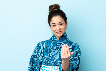 Woman wearing kimono over isolated background inviting to come with hand. Happy that you came