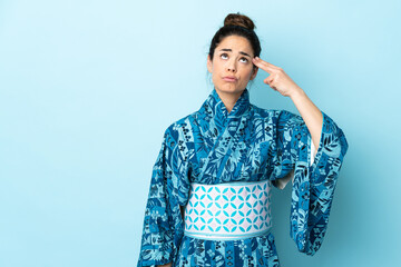 Woman wearing kimono over isolated background with problems making suicide gesture