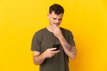 Young caucasian handsome man isolated on yellow background thinking and sending a message