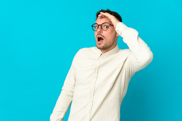 Young caucasian handsome man isolated on blue background doing surprise gesture while looking to the side