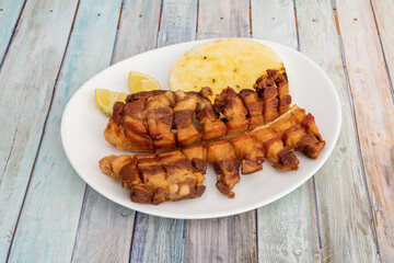Latin American chopped chicharrón fried in lard, lemon wedges and corn arepa