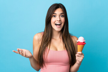 Teenager Brazilian girl holding a cornet ice cream over isolated blue background with shocked...