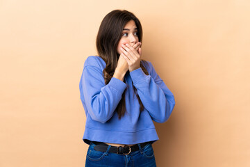 Teenager Brazilian girl over isolated background covering mouth and looking to the side