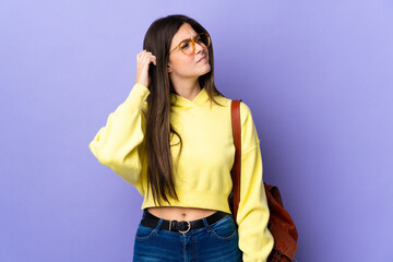 Teenager Brazilian student girl over isolated purple background having doubts and with confuse face expression