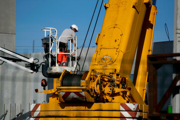 Cranes and lifts carrying concrete walls for installation on a warehouse and office construction site