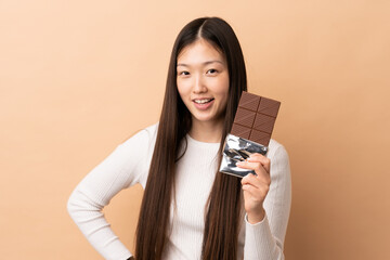 Young Chinese girl over isolated background taking a chocolate tablet and happy