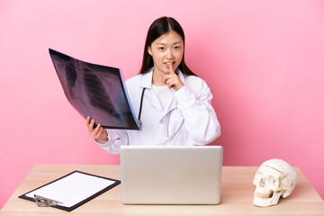 Professional Chinese traumatologist in workplace doing silence gesture