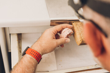 Hands of a professional moulding the pieces with wax in a dental laboratory specialised in dental bone ceramics