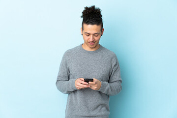 Caucasian man over isolated background sending a message with the mobile