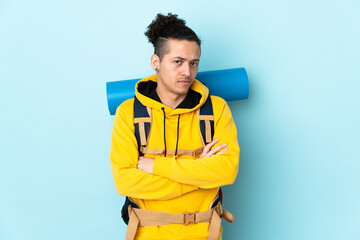 Young mountaineer man with a big backpack over isolated blue background thinking an idea