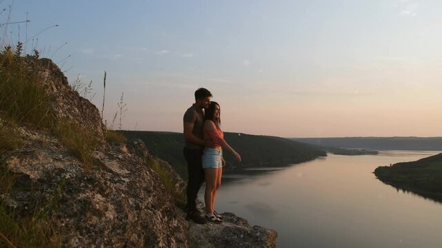 The romantic couple standing on rocky mountain top above the river. slow motion