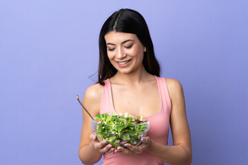 Young woman with salad over isolated purple background