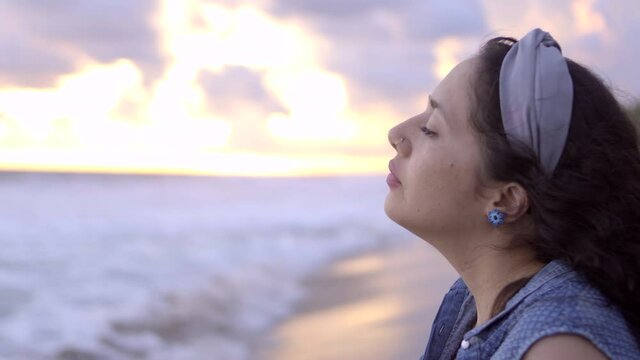Mujer latina relajada inhala profunda bocanada de aire del mar al atardecer en la playa en Pie de la Cuesta, Acapulco, México
