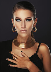 Beautiful woman with evening make-up and gold jewelry.