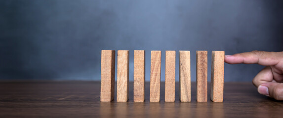 Close-up fingers prevent the wooden block from falling domino concepts of financial risk management...