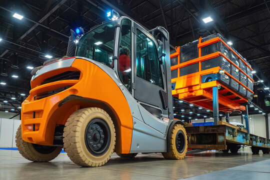 Forklift truck during work. She is engaged in loading cargo onto the platform. Concept - warehouse special equipment. Small car with stackers function. Forklift truck inside warehouse.
