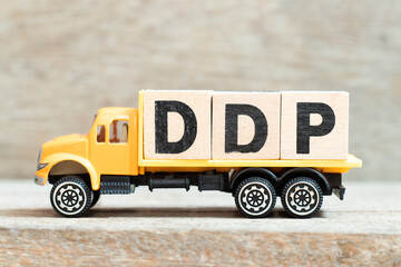 Toy truck hold alphabet letter block in word DDP (Abbreviation of Delivered duty paid) on wood...