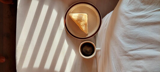 Black coffee and sandwich on white sofa in morning time .It space background for  put document...