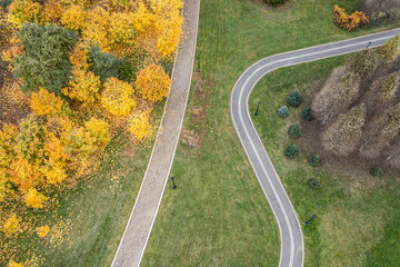 walking path and bicycle lane in public park with colorful autumn trees. aerial photo, top view.