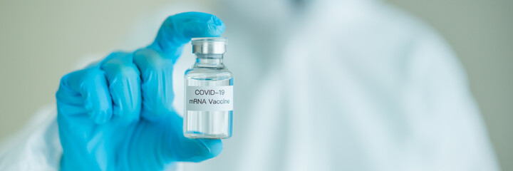 Unrecognizable specialist doctor in a medical PPE suit showing a coronavirus SARS 2019-nCoV or COVID-19 mRNA vaccine.