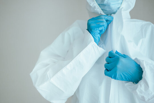 Unrecognizable specialist doctor dress up a medical PPE suit before working in hospital.  - Powered by Adobe