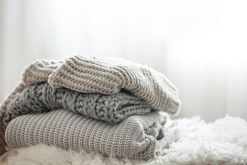 Fototapeta na wymiar Cozy gray knitted sweaters stacked on blurred background, copy space.