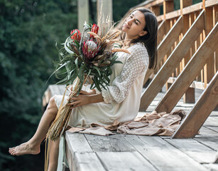 Portrait of an attractive young woman with a bouquet with protea flowers.