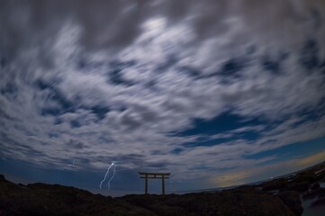 The traditional gate outside at the sea shore and lightnings in the night in Japan