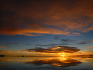 Fototapeta na wymiar ボリビアのウユニ塩湖にて水面に鏡のように反射するオレンジ色の夕日